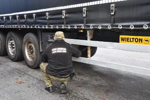Funkcjonariusz Straży Granicznej dokonuje kontroli naczepy zestawu ciężarowego