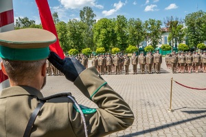 Funkcjonariusz NOSG oddaje honor podczas uroczystego wciągnięcia flagi na maszt