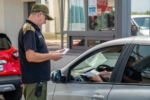 Funkcjonariusz SG prowadzi odprawę paszportową na terenie drogowego przejścia granicznego