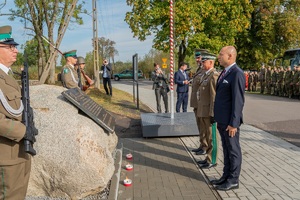 Zapalenie zniczy pod pamiątkową tablicą przez uczestników uroczystości