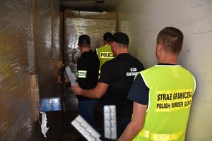 Funkcjonariusze służb zabezpieczają nielegalne papierosy w naczepie tira