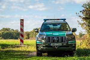 Pojazd służbowy SG obok polskiego znaku granicznego