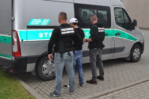 Funkcjonariusze SG doprowadzają do pojazdu służbowego osobę zatrzymaną