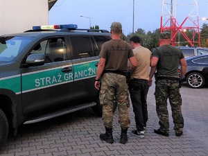 Funkcjonariusze Straży Granicznej podczas doprowadzenia do pojazdu służbowego osoby zatrzymanej